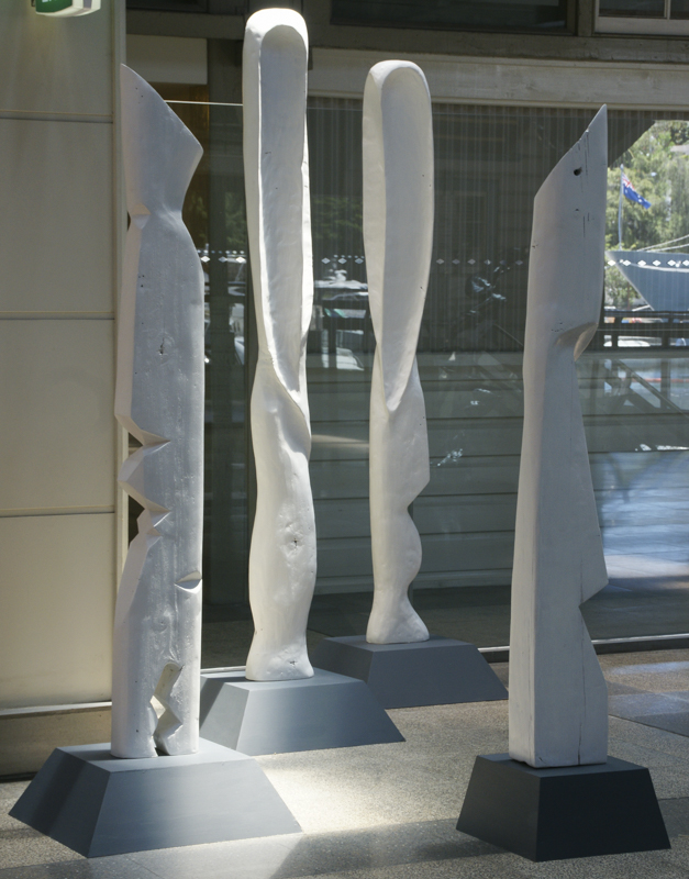 Four tall carved wood sculptures from sculpture series displayed in exhibition space in Ovolo Hotel Sydney